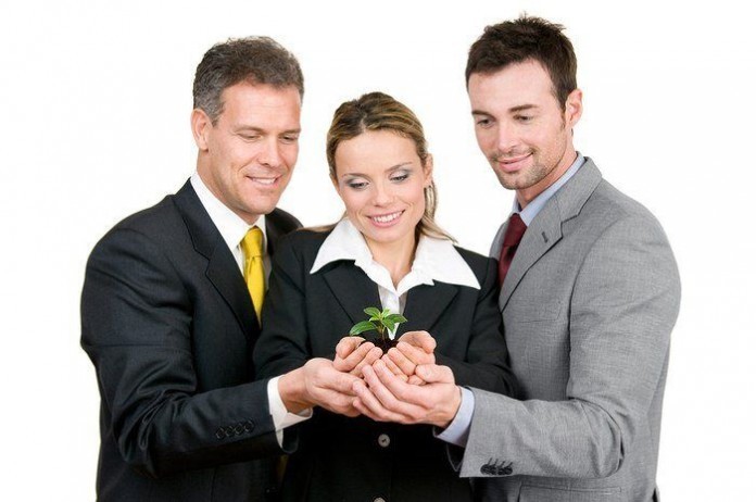 Business team holding a fresh new plant on palm, symbol of green Business retail team