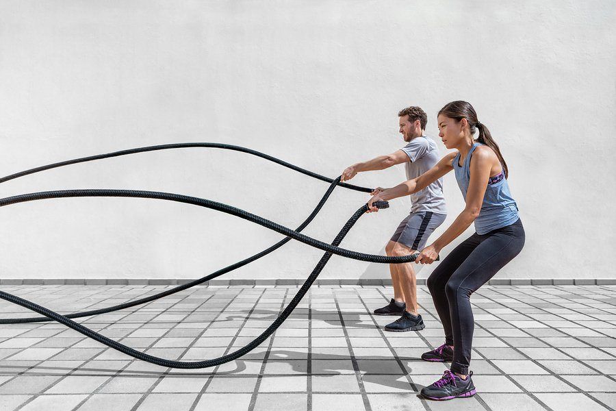 Fitness people exercising with battle ropes at gym