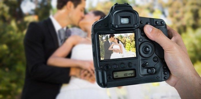 photographer holding camera at newlywed couple wedding photography