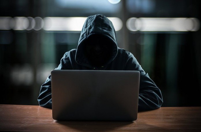 Hacker in front of his computer. Dark face Hacker in front of his computer