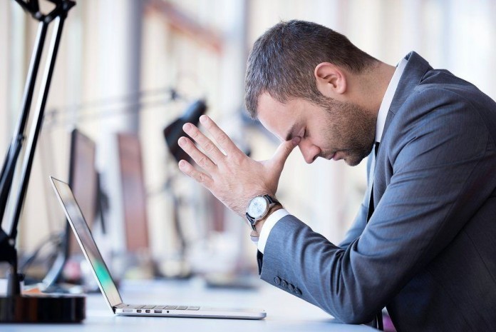 frustrated young business man working on laptop computer at offi stressful work