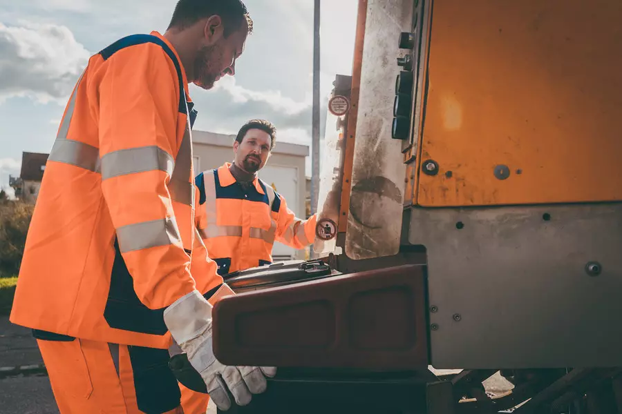 Garbage removal men working for a public utility emptying trash