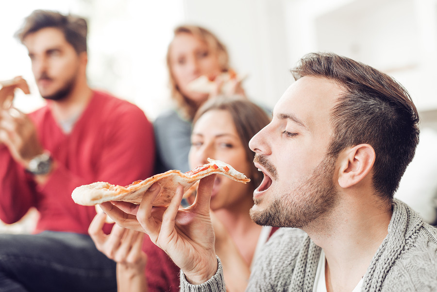 Friends and pizza.Four young cheerful people eating pizza at home.