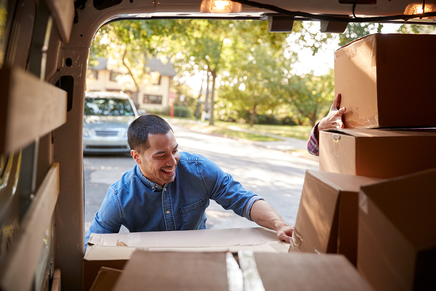Couple Unloading Boxes From Van On Family Moving In Day
