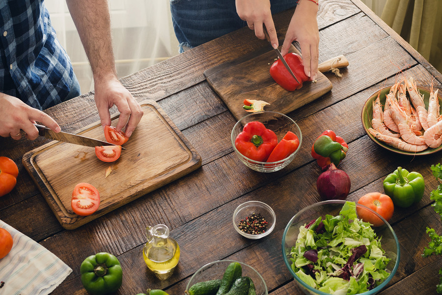 Top view couple cooking together delicious and healthy dinner on a wooden table in home kitchen