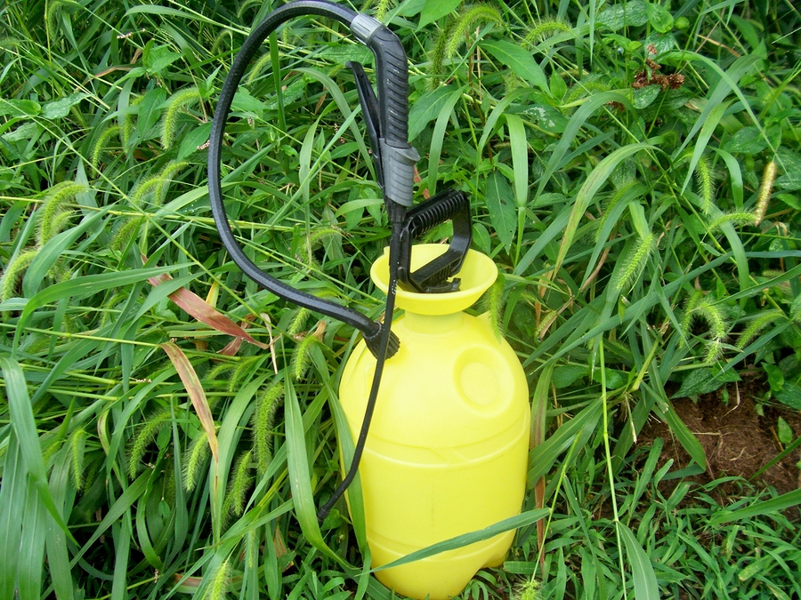 Photo of a chemical sprayer sitting in tall grass.