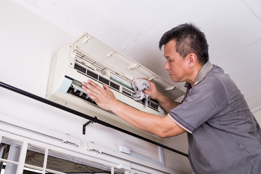 Series of technician servicing the indoor air-conditioning unit. Cleaning with cloth.