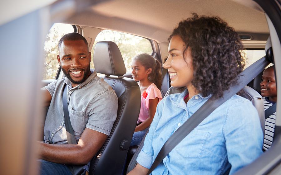 Young black family in a car on a road trip smiling
