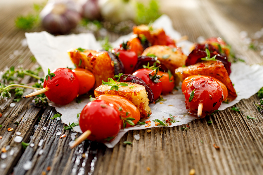 Vegetarian skewers with halloumi cheese, cherry tomatoes, red onion and fresh herbs on a wooden rustic table