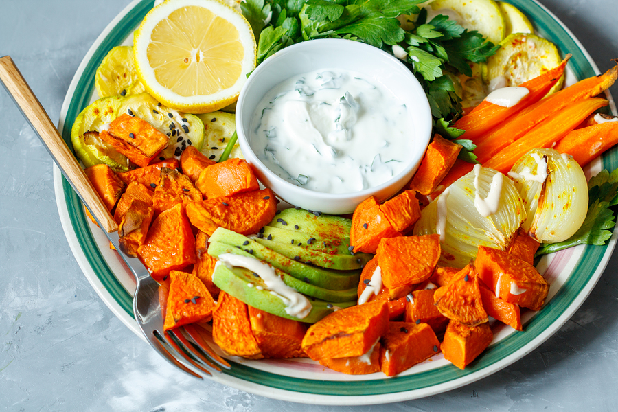 Baked sweet potato zucchini and carrots with sour cream sauce on a plate.
