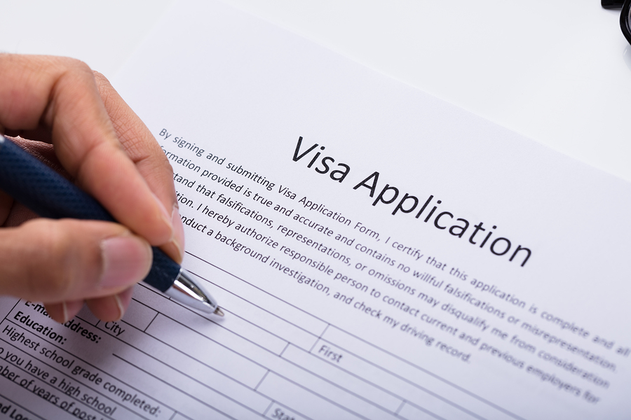 Close-up Of A Person's Hand Filling Visa Application Form