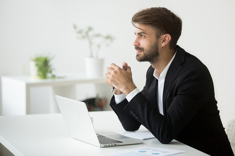 Young dreamy businessman in suit thinking of business vision outlook planning future project idea at work with laptop, successful happy contemplative entrepreneur dreaming of new opportunity prospect