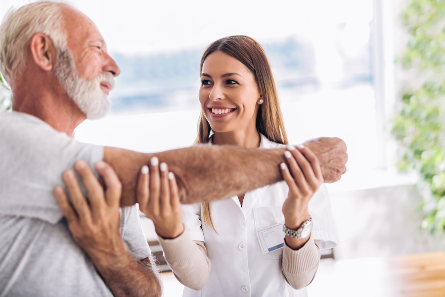 Man having chiropractic arm adjustment. Physiotherapy, sport injury rehabilitation. Senior man exercises in center for chiropractic.