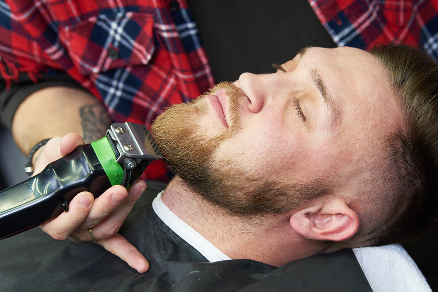 Beard care. man while trimming his facial hair cut at the barbershop