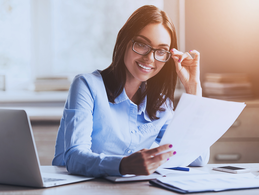 Young Pretty Lady Reading Documents and Smiling while Working in Office. Accountant Manager. Office Administrator. Workday in Office. Work and Job Concepts. Smiling Businesswoman. Business Concept.