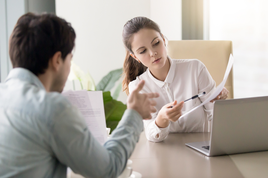 Businessman and businesswoman discussing papers concerning new business project during meeting at office, colleagues preparing important documents, partners negotiating under contract, teamwork