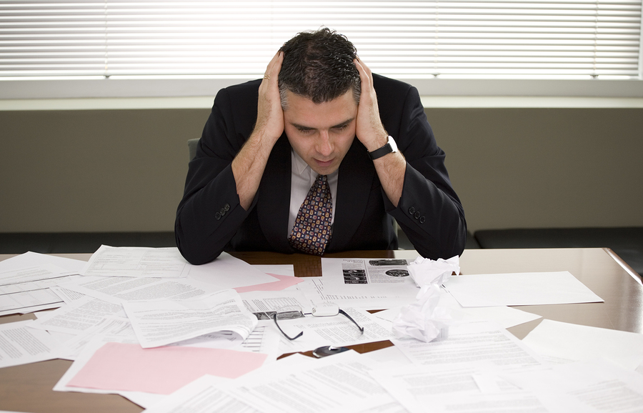 A businessman pondering over a pile of paperwork