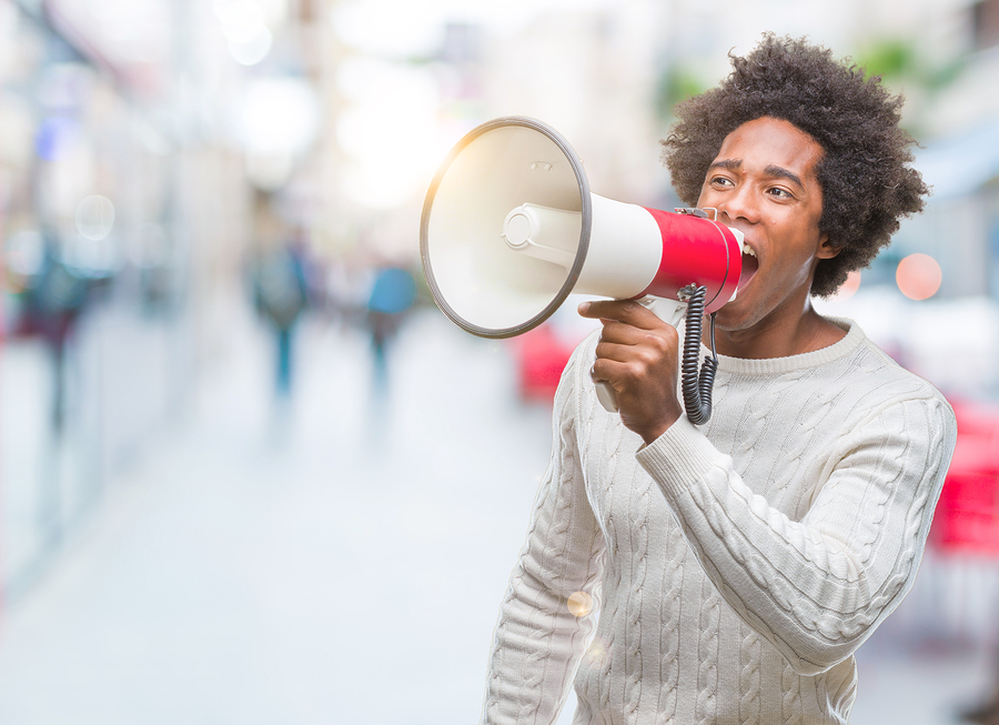 Young handsome afro american black man shouting through megaphone