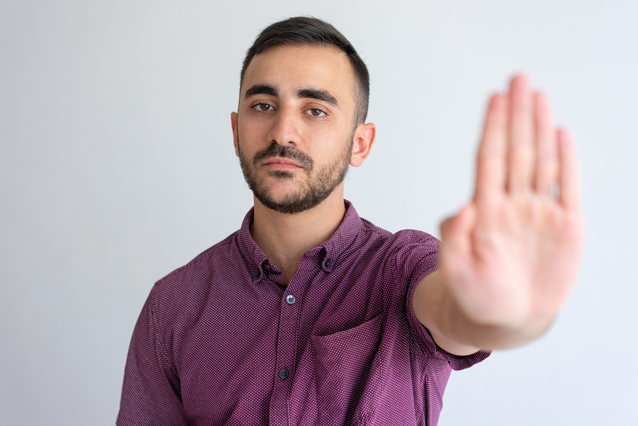 Strict businessman in casual gesturing stop. Young man raising hand and showing palm in prohibited sign. Prohibition concept