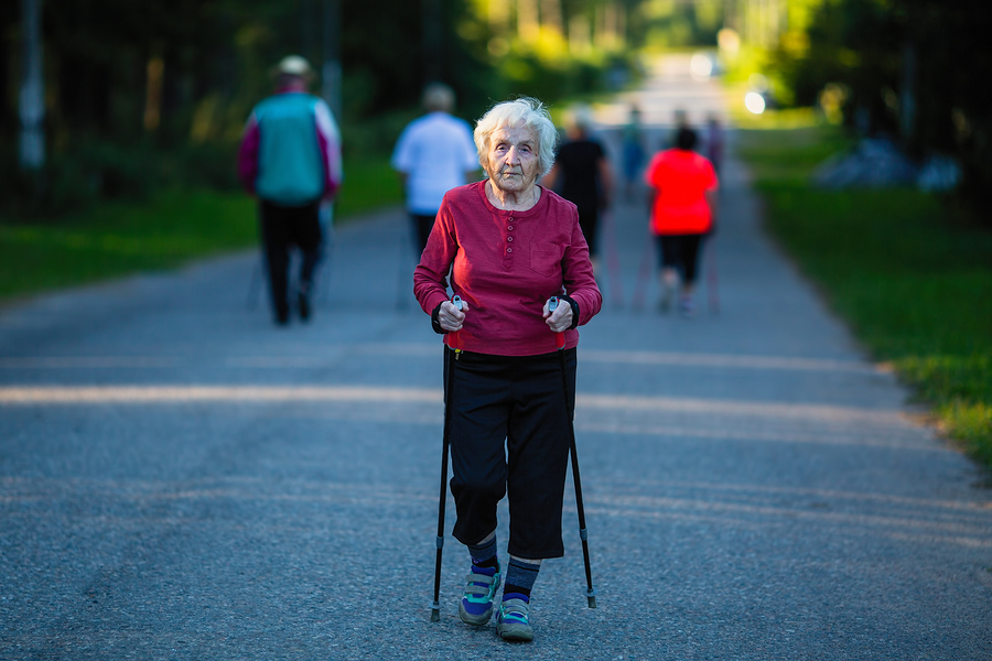 Elderly woman engaged in Nordic walking with sticks.