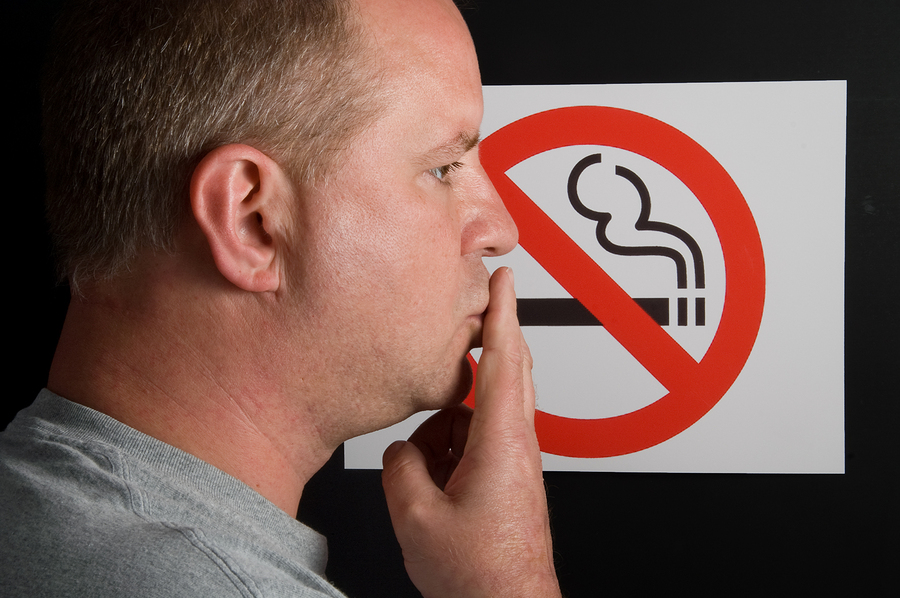 A man smoking a no smoking sign.