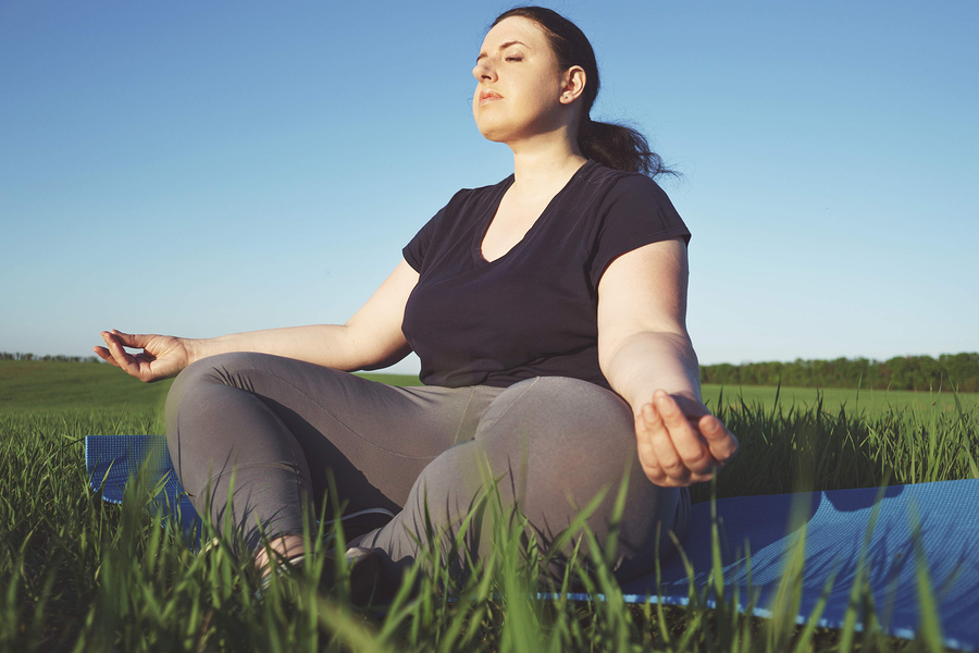 Body positive, yoga, meditation, tranquility, relax. Overweight woman meditating sitting at yoga mat outdoors. high self esteem, no complex, free your mind concept