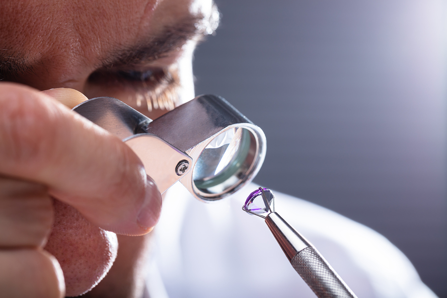 Close-up Of A Male Jeweler's Hand Looking At Diamond Through Magnifying Loupe