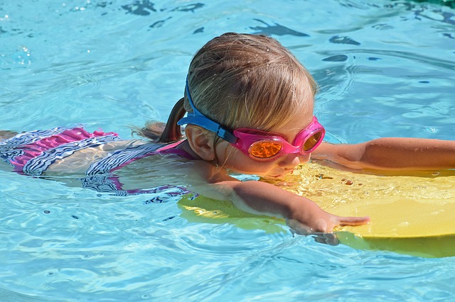 Young girl swimming in pool with goggles