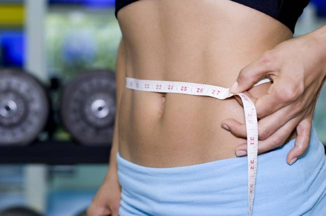 A female fitness instructor measures her waist