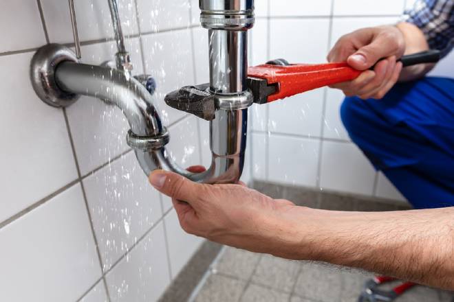 Male plumber's hand repairing sink pipe leak