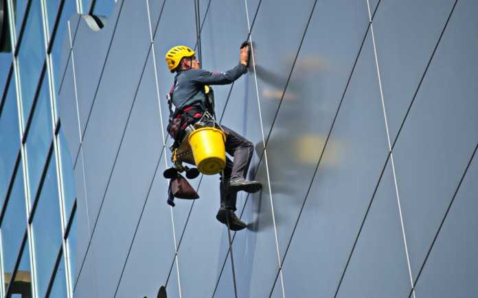 Best Window Cleaners in Newcastle Man cleaning the glass window of a building.