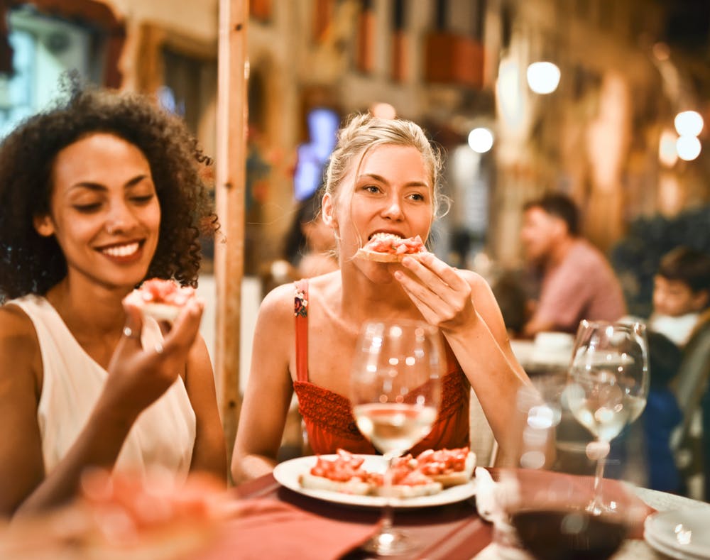 Two women eating pizza in an Italian restaurant.