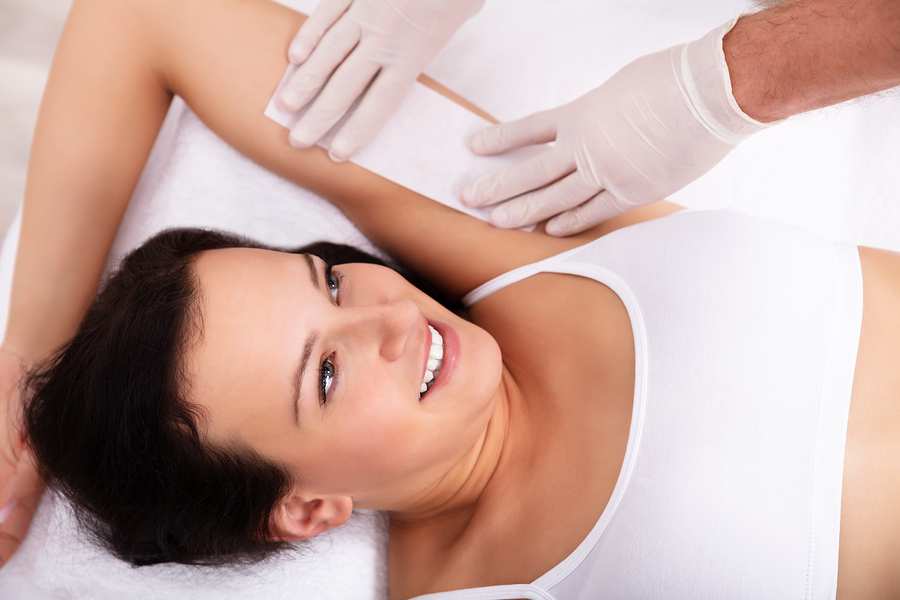 Woman with her armpit getting waxed.