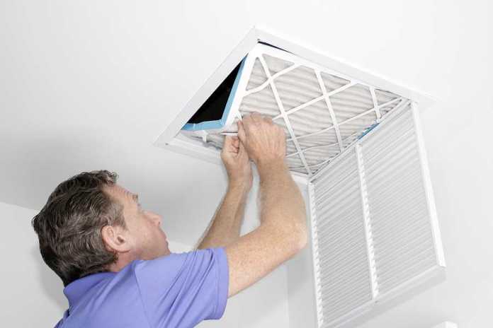 Best HVAC Services in Newcastle Man removing a dirty air filter in a house from a HVAC ceiling air vent.