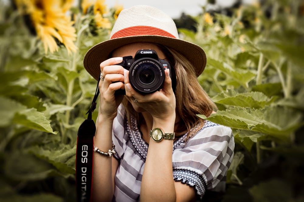 Woman holding a camera as she takes pictures.
