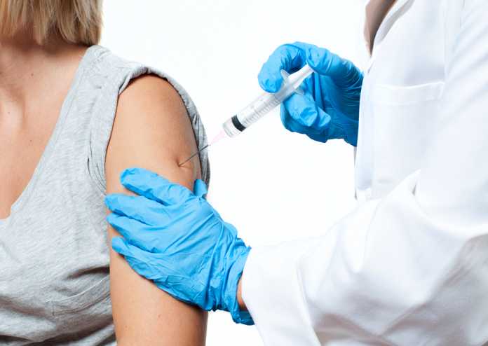 Vaccination. Doctor Injecting Flu Vaccine To Patient's Arm. How to organise workplace flu vaccinations in Sydney