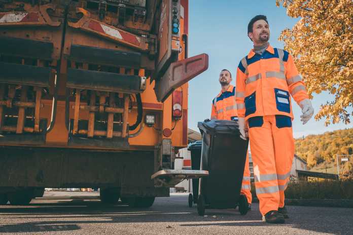 Garbage removal men working for a public utility emptying trash The art of effective rubbish removal