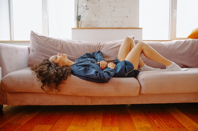 A woman with abdominal muscle separation lying on a couch holding her stomach.