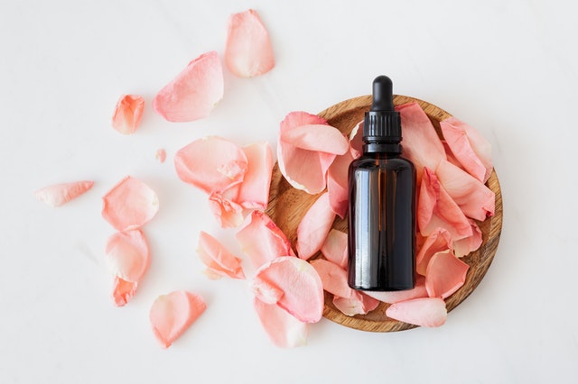 Essential oil from a best cosmetic wholesaler in a bowl of rose petals.