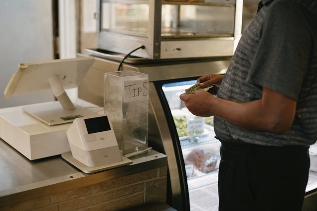 A customer with cash at a point of sale system.