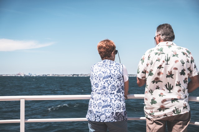 A man and a woman looking out at a port from the railing of their 2022 Australian cruise ship.