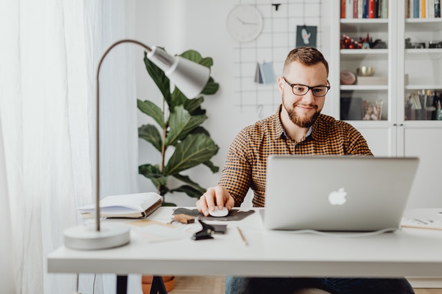 A man sitting at a desk smiling at his laptop as his small business gets more visibility with SEO.