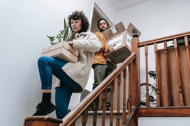 Two Sydney apartment investors carrying boxes down the stairs.