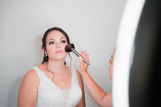 A bride having her makeup done because she has her kids at her wedding and needs to delegate.